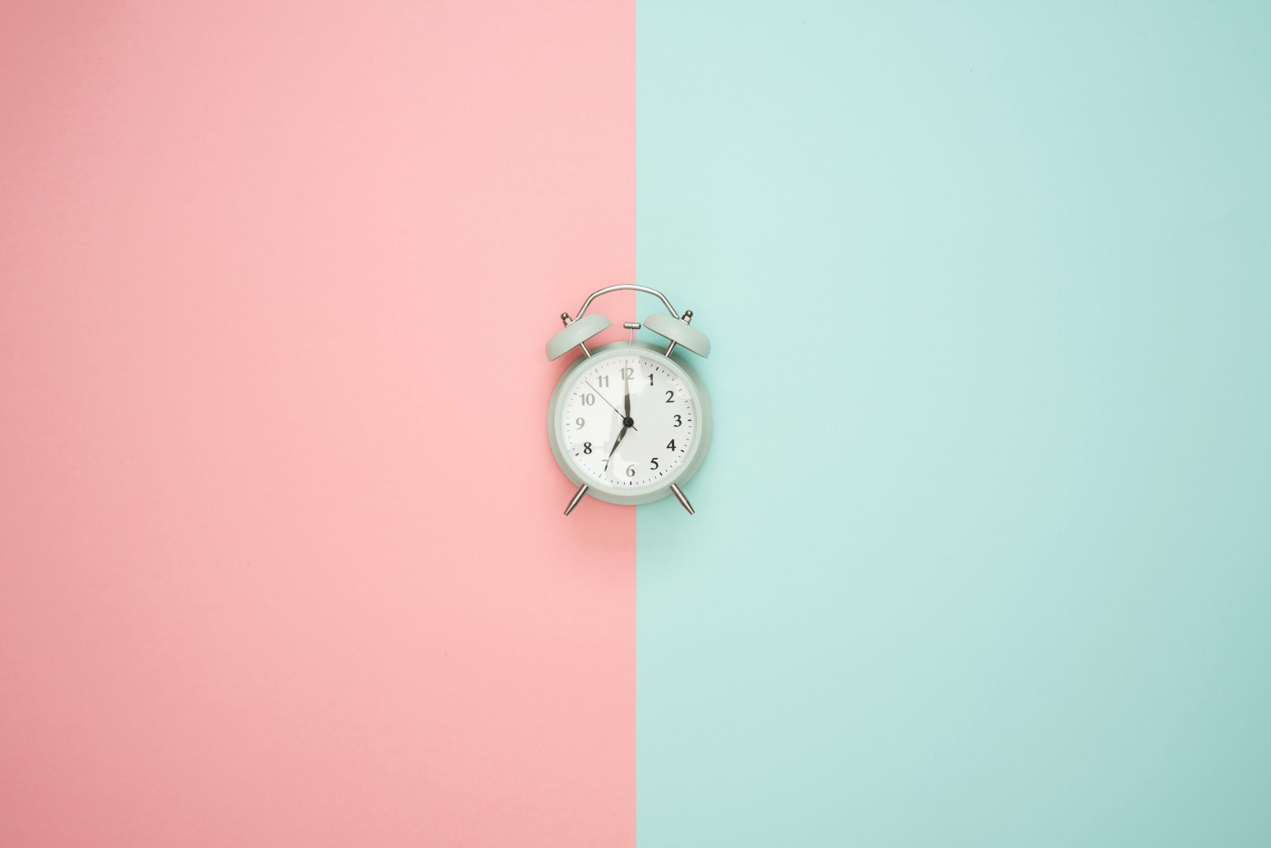 Time Clock Understanding web development timelines: A clock in front of a two tone background split in half between pink and green.